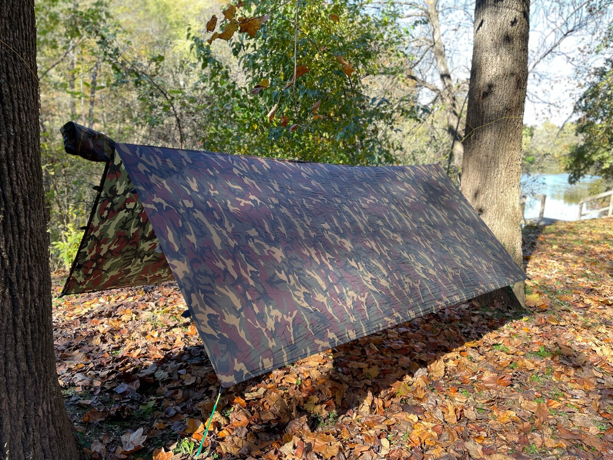Jacks R Better camo hammock tarp pitched in an A-frame lean-to beside a lake in autumn