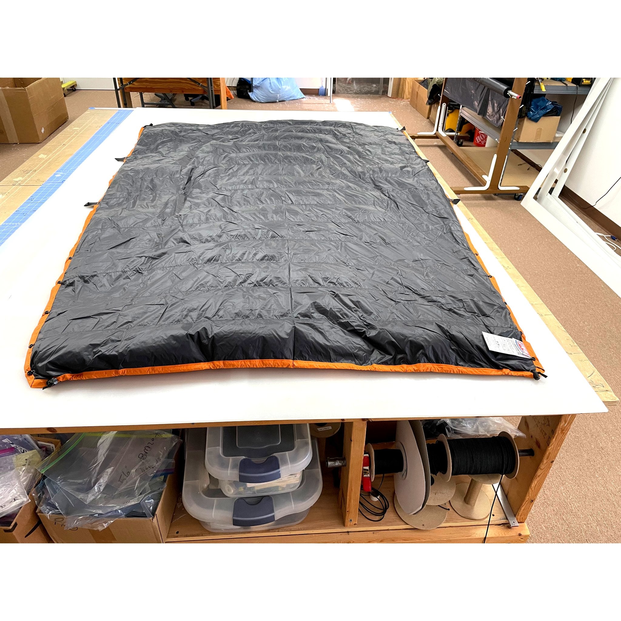 Custom ultralight backpacking quilt in Black with Burnt Orange edge trim, laid flat