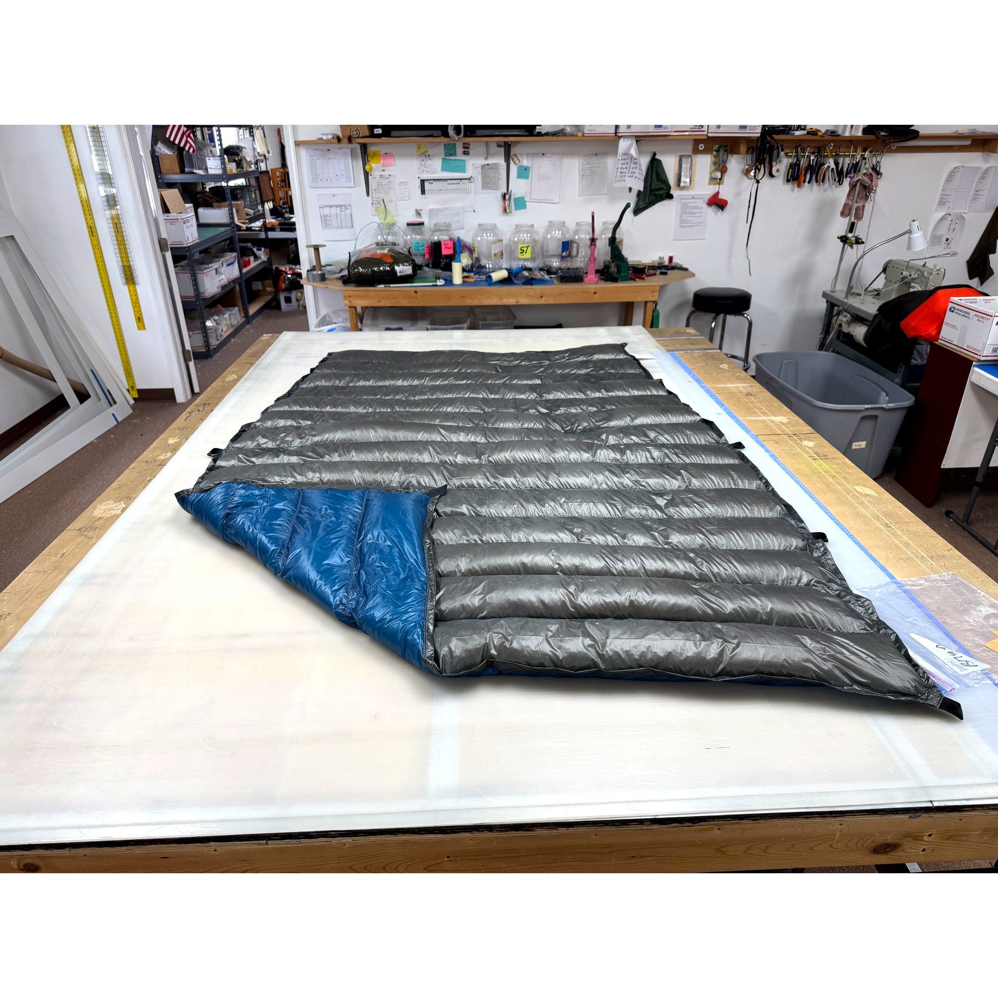 Custom ultralight backpacking quilt with a Charcoal Grey shell and Brilliant Blue lining shown at the folded corner