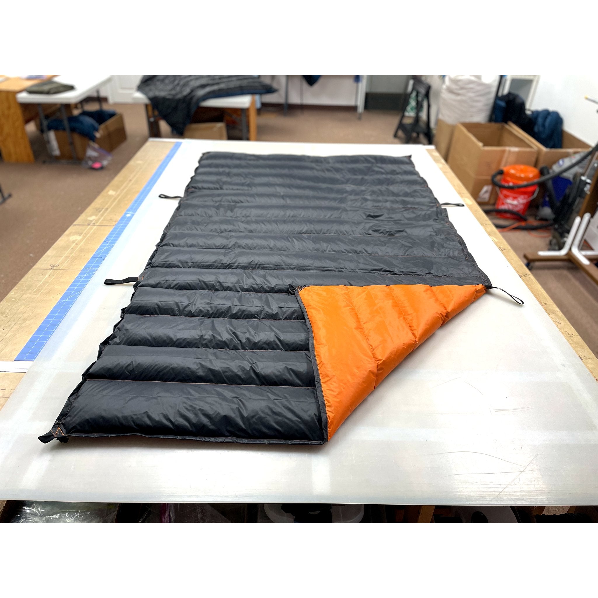 Custom ultralight backpacking quilt with a Charcoal Grey shell and Burnt Orange lining at the folded corner