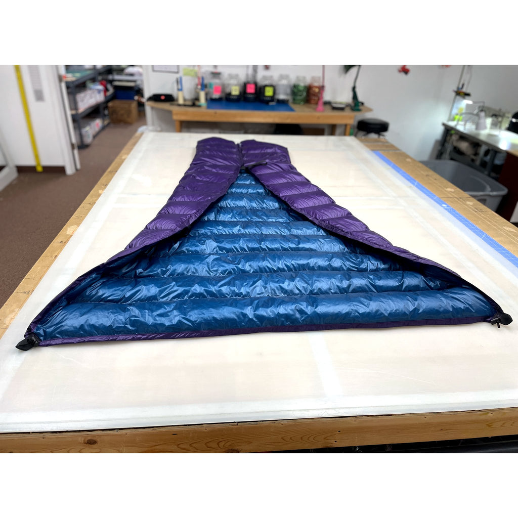 Custom ultralight backpacking quilt with a Moroccan Blue shell and Purple lining, opened to show the interior