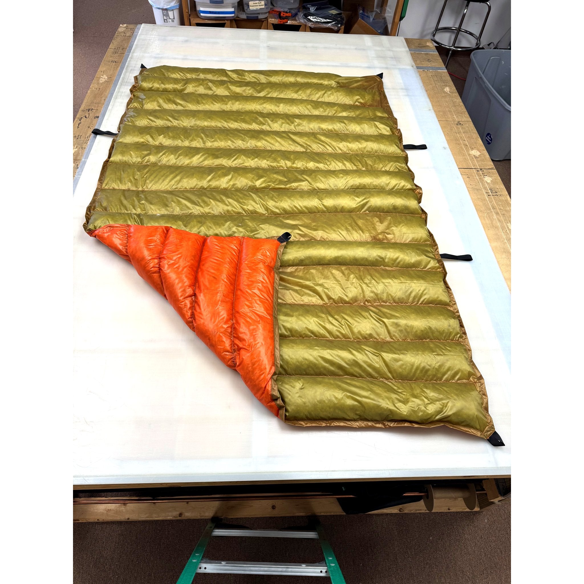 Custom ultralight backpacking quilt with a Moss Green shell and Burnt Orange lining, corner folded back