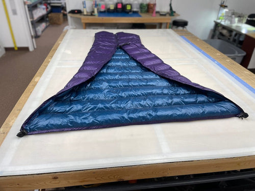 Custom ultralight backpacking quilt in Purple and Moroccan Blue, opened flat to show the two-tone interior